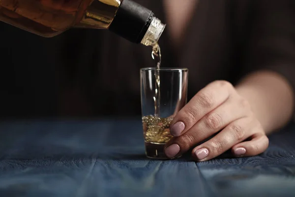 Mujer vertiendo whisky en el vaso de chupito — Foto de Stock