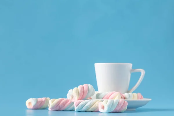 Pastel marshmallow e uma xícara branca em um fundo azul. Doce u — Fotografia de Stock