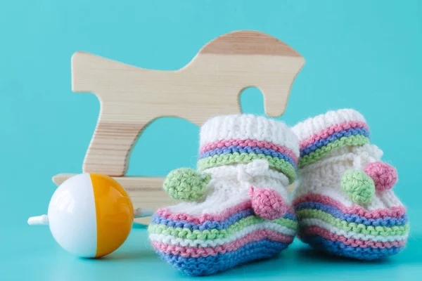 Botines de bebé con sonajero sentado sobre un fondo aguamarina — Foto de Stock