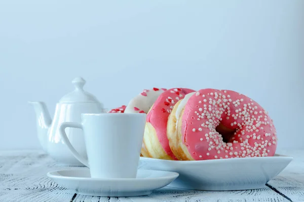 Donuts con glaseado blanco y rociado sobre tabla de madera con taza de café — Foto de Stock
