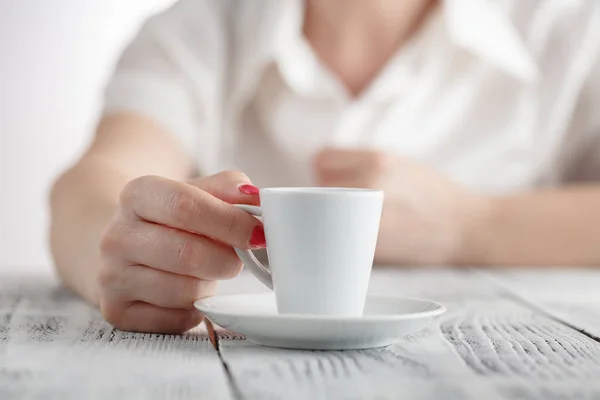 Жінка з червоними цвяхами сидить і тримає гарячу чашку кави — стокове фото