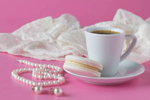 Cup of coffee, pearl necklace on pink background. Spring romanti