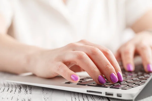 Closeup of business woman hand with manicure typing on laptop keyboard