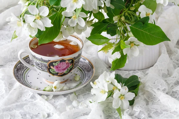 Filiżanka herbaty na drewnianych blossom tabeli i apple. Pojęcie czasu herbaty. Filiżanka herbaty śniadanie serwowane z kwiatami. — Zdjęcie stockowe