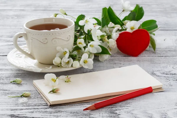 Xícara de chá e flor de sakura rosa em um velho fundo de madeira — Fotografia de Stock