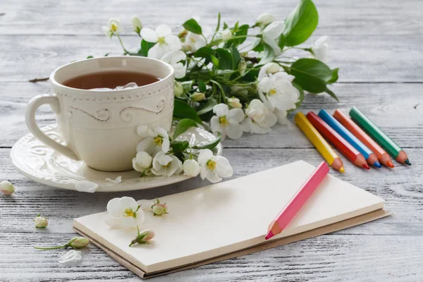 Eski ahşap masada boş kağıt ve renkli kalemler.