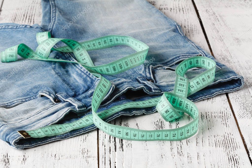 Measuring tape on blue jeans at waist