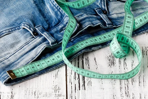Fita métrica e jeans com fundo de madeira — Fotografia de Stock