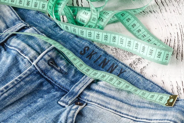 Jeans e uma fita de medição. Conceito de perder peso. Frutas para — Fotografia de Stock