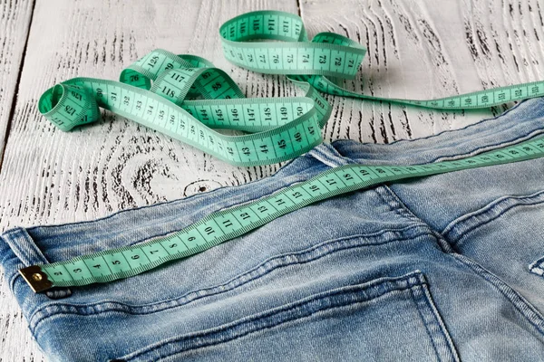 Jeans blu e nastro di misurazione in vita e in corpo su legno b — Foto Stock