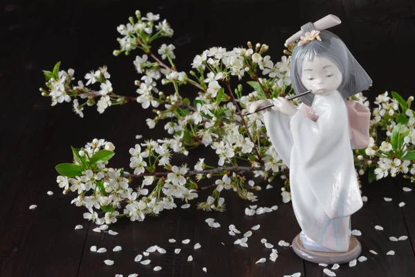 Figurilla de cerámica frente a flores de cerezo, primer plano — Foto de Stock