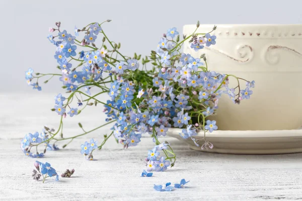 Tasse Tee und vergiss mich nicht Blumen auf einem hölzernen Hintergrund — Stockfoto