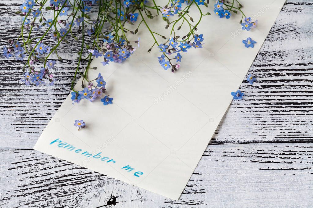 Forget-me-nots flowers with card on a wooden background