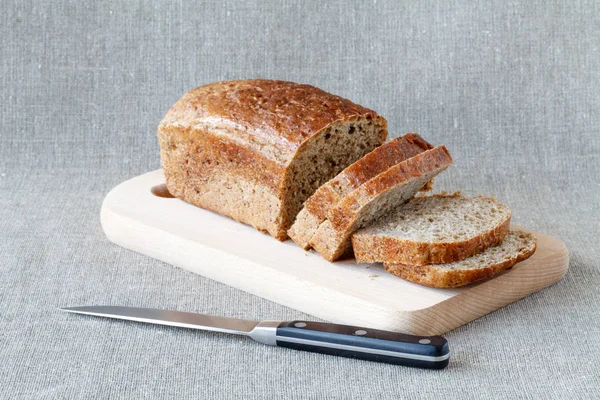 Szeletelt teljes kiőrlésű kenyér fából készült asztalon — Stock Fotó