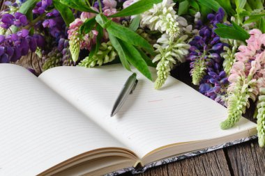 boş defter ile kalem ve buket çiçek ahşap masa. günlük yazma kavramı