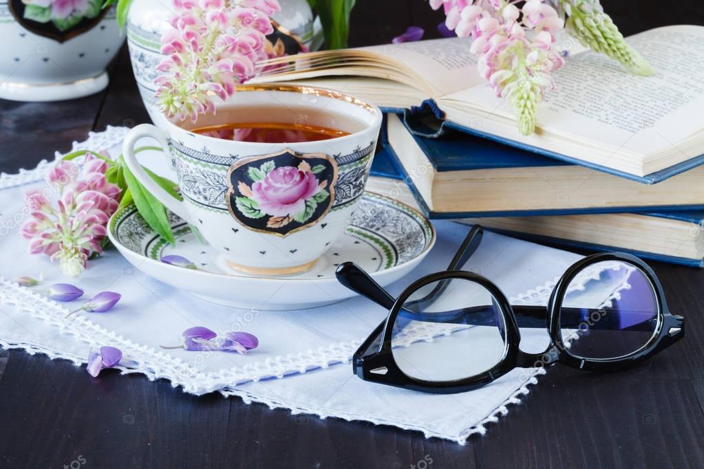 Cup of tea with books and flowers on wooden background — Stock Photo