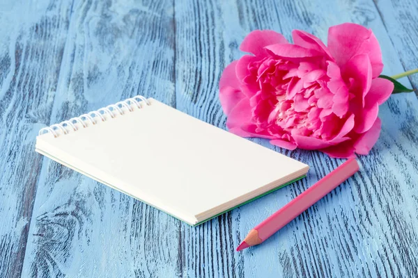 Quaderno con una matita e peonie fiori sul retro di legno — Foto Stock