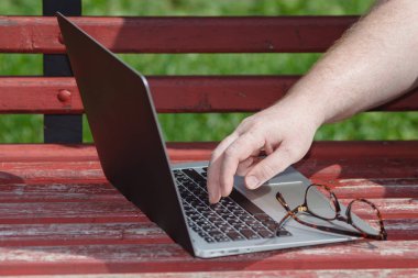 Bir el parkta bir dizüstü bilgisayarda yazarak meşgul closeup