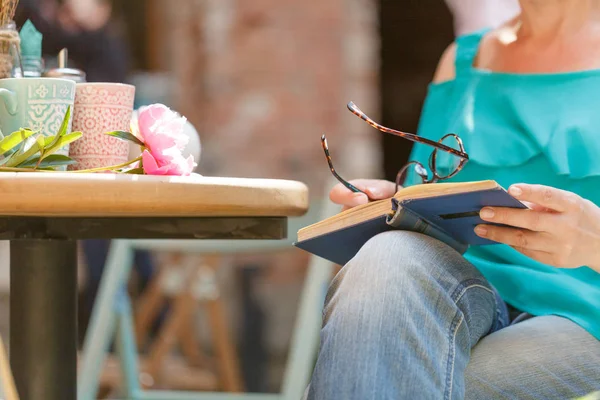 Bonita mulher sentada à mesa no café e livro de leitura — Fotografia de Stock
