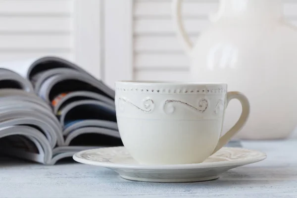 Пачка журналов и чашка белого кофе на белом фоне . — стоковое фото
