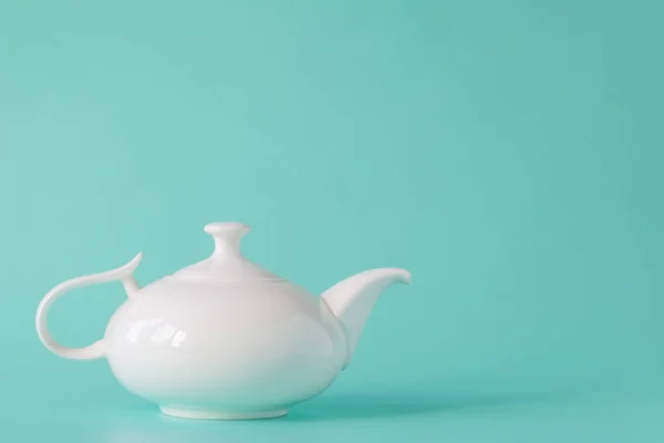Белый чайник изолирован на аквамариновом фоне — стоковое фото