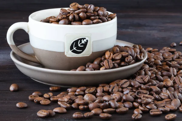 Närbild av kopp espresso med färska bönor på ett träbord — Stockfoto