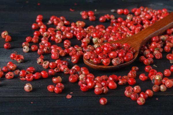 Rose pepper in wooden spoon black background