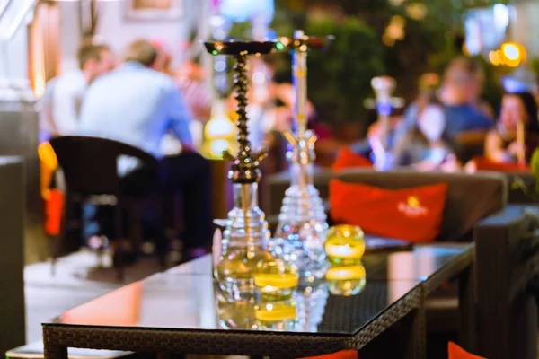 bar for smoking a hookah. The background is blurred. In the foreground is a big hookah