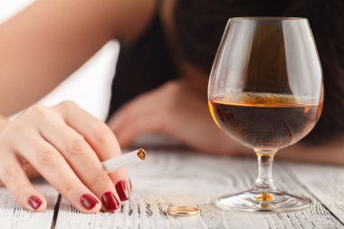 bir alkollü içki holding ve başını masanın üzerinde uyuyan sarhoş kadın (içki üzerinde duruldu, yüzünü odak dışında olduğunu)