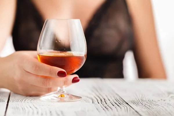 Main féminine tenant un verre de cognac — Photo