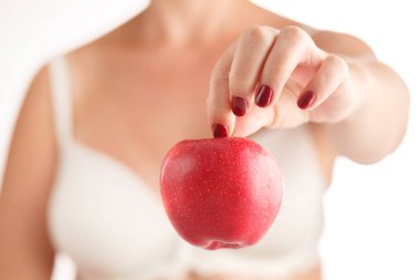 Kırmızı manikür üzerinde tutan bir kırmızı ve sarı elma ile eller