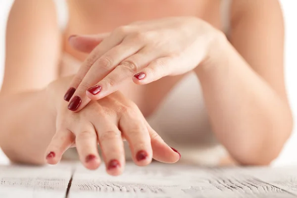 Women's handen met rode manicure aanbrengen van de crème — Stockfoto