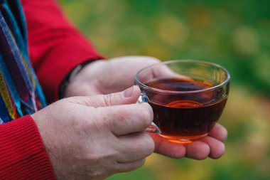 Adam akçaağaç yaprakları ile sonbahar Parkta yürümek çay fincan