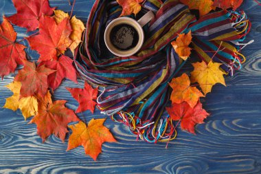 Fincan kahve, sonbahar yaprakları ve sıcak bir eşarp siyah ahşap tabl üzerinde