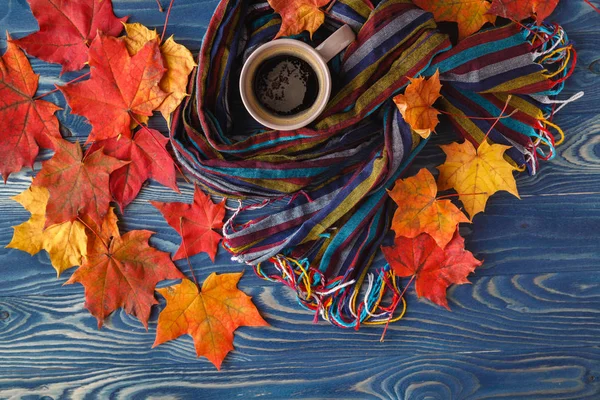 Fincan kahve, sonbahar yaprakları ve sıcak bir eşarp siyah ahşap tabl üzerinde