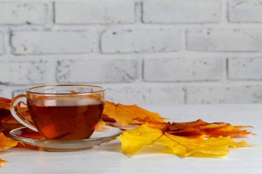 Sonbahar yaprakları, dumanı tüten fincan sıcak çay ahşap arka plan üzerinde