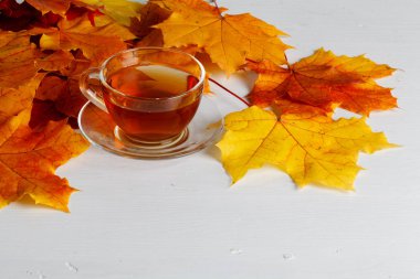 Sonbahar yaprakları, dumanı tüten fincan sıcak çay ahşap arka plan üzerinde