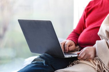 Dizüstü evde oturma odasında kullanarak katta oturan genç adam