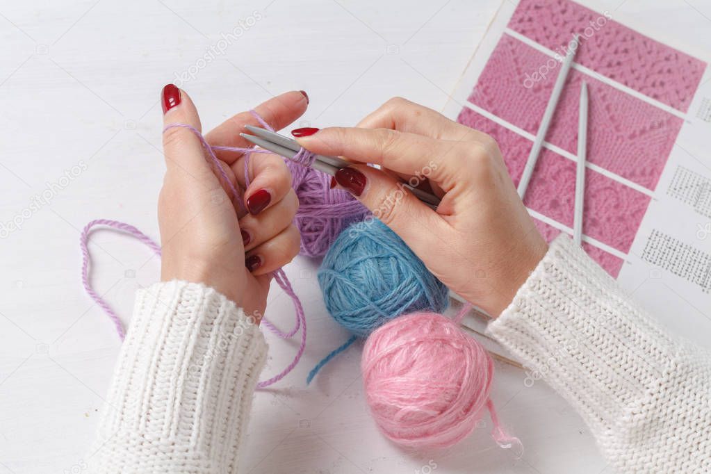 Caucasian woman knits woolen clothes. Holding knitting needles at hands