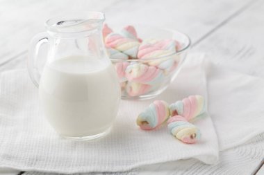 Beyaz ve pembe bükülmüş krema ve süt beyaz ahşap bir masa üzerinde bir sürahi. Güzel açık renkli. 