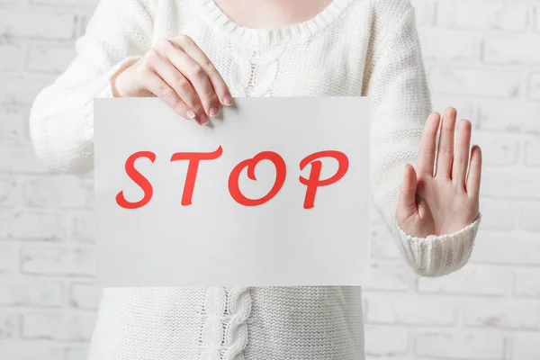 Giovane ragazza che tiene un segno bianco con iscrizione rossa STOP su un w — Foto Stock