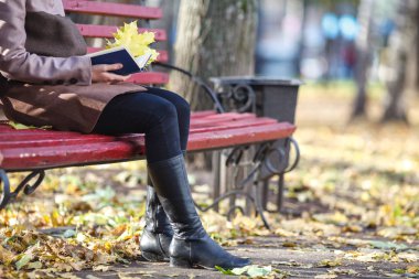 Park'ta rahatlayın. Kitap bankta oturan genç güzel kadın. Au