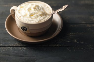 Manzaralı cappuccino kahve ahşap masada beyaz köpüğe odaklanmış.