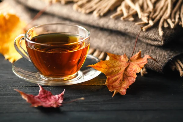 Herbst-Stillleben mit Tasse Tee, Karo und Blättern auf Holzbalken — Stockfoto