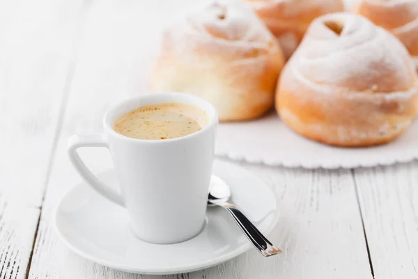 Tasse schwarzen Kaffee und süßes Brötchen zum Frühstück, Nahaufnahme — Stockfoto