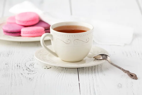 Coloridos macarrones franceses y una taza de té en una espalda de madera rústica — Foto de Stock