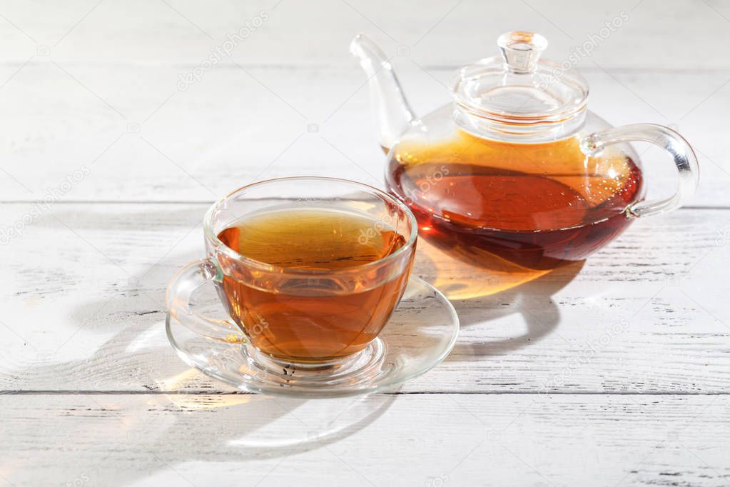Tea in glass with tea being brewed in a glass jug placed on a ta