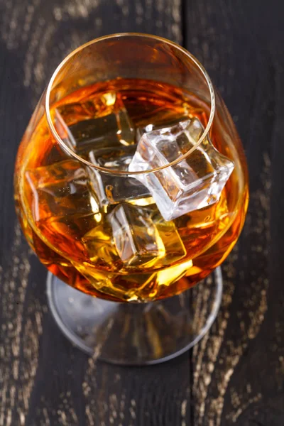 Vaso de whisky con hielo servido sobre tablones de madera. Encimera vintage con resaltado y un vaso de licor duro —  Fotos de Stock
