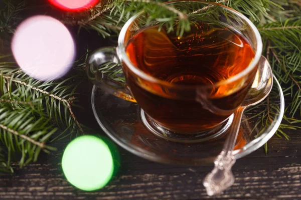 Cup of tea and branch with Christmas lights on background. — Stock Photo, Image