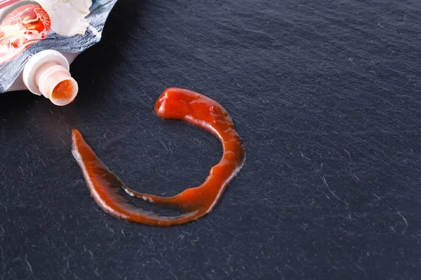 Vista de perto do ketchup de tomate no quadro de ardósia — Fotografia de Stock